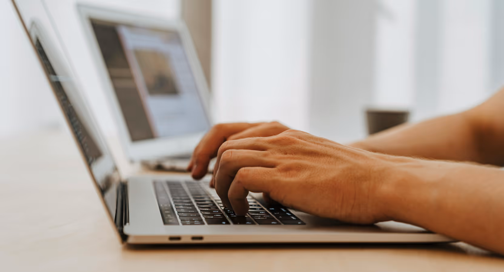 Person typing on a laptop, focused on coding for accessible HealthTech applications.