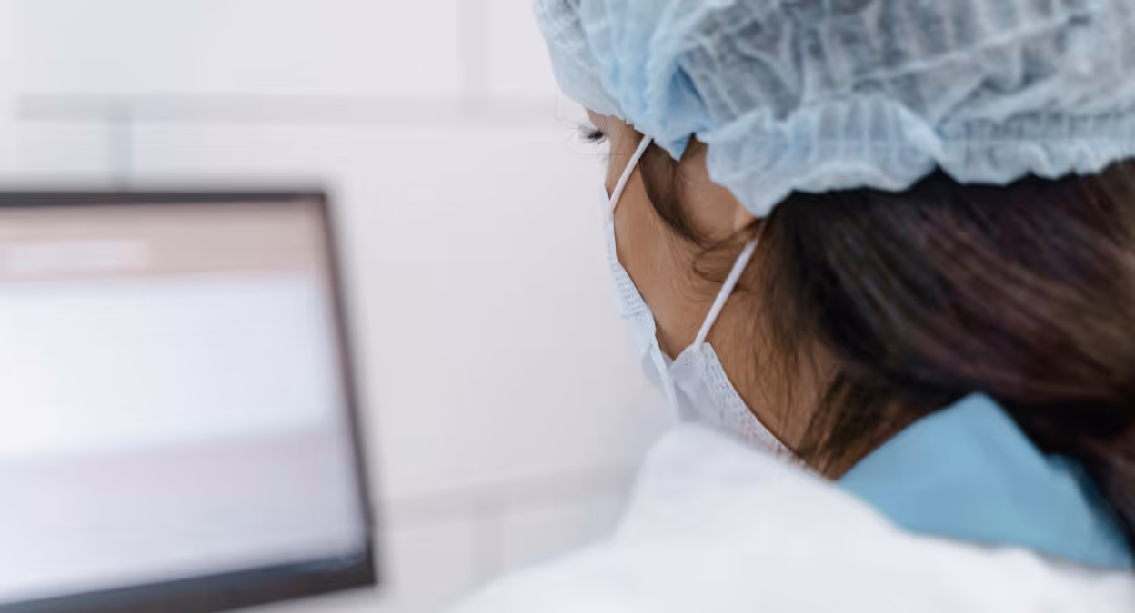 Healthcare professional using a computer workstation in a clinical setting.