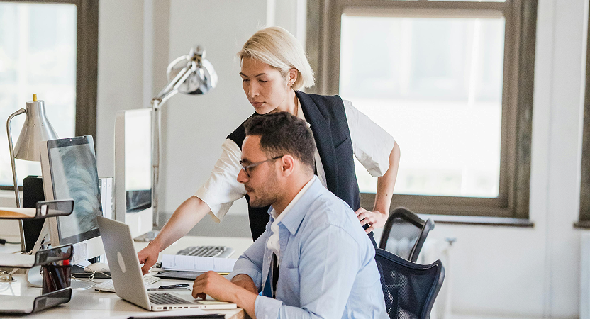 Colleagues reviewing healthcare data on a laptop screen in a modern office setting
