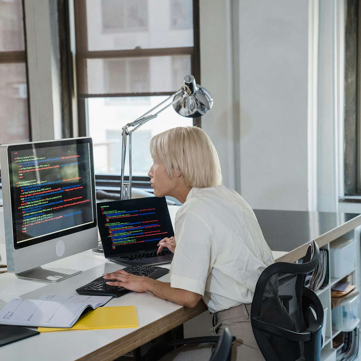 Close-up of developer comparing code across two screens, refining tests and API integrations with help from AI coding tools.