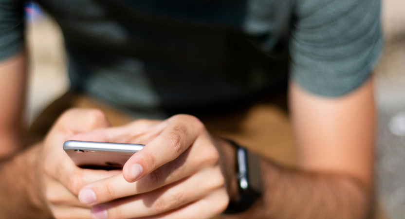 A man closely holding a smartphone, engaged with the screen, likely exploring health-related features.