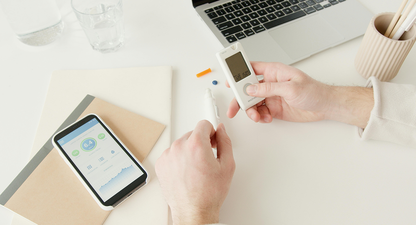Close-up of a user with a glucose monitor and smartphone health tracking app – representing mobile-first use cases in chronic condition management.