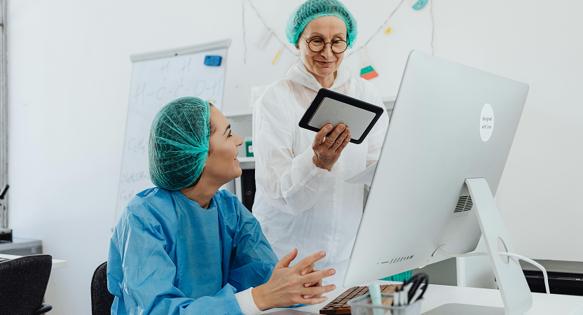 Healthcare professionals reviewing data on desktop and tablet in a clinical setting – illustrating dual-platform use and web-first environments.