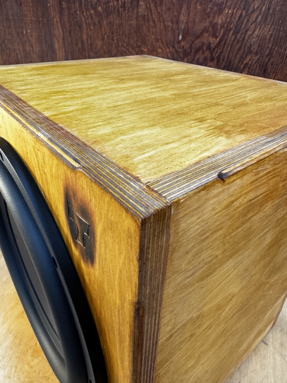 Atomic Subwoofer top corner view of Baltic Birch construction with view of carved tiki "T" logo handmade by Tiki Tube Amps