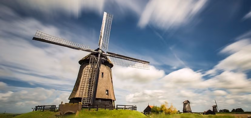 Molinos de viento tradicionales holandeses en un paisaje verde y nublado