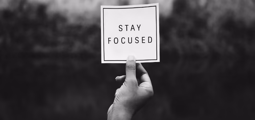 Hand holding a black and white card with the text “Stay focused”