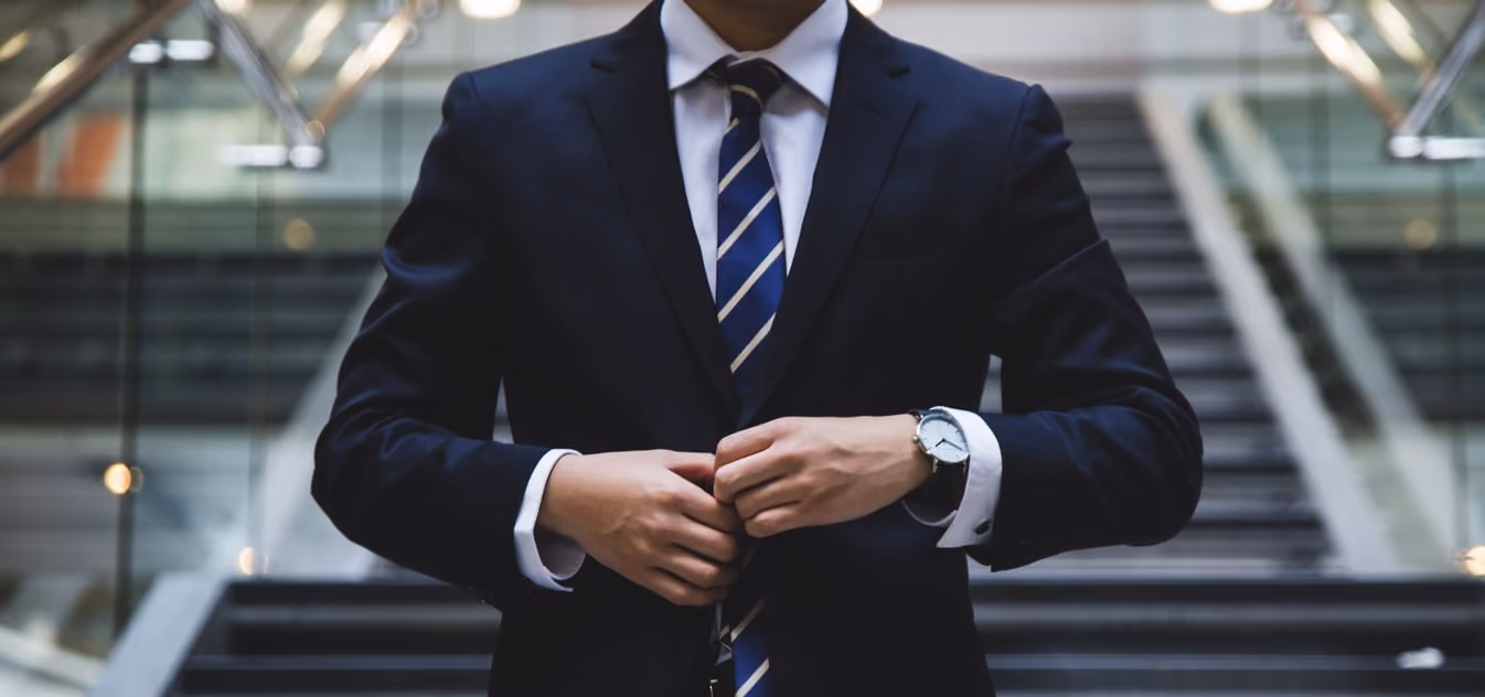Executive in navy blue suit and tie fitting his jacket in office