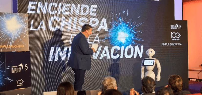 Robot humanoide sobre la tarima del auditorio acompañado de Ángel Uzquiza