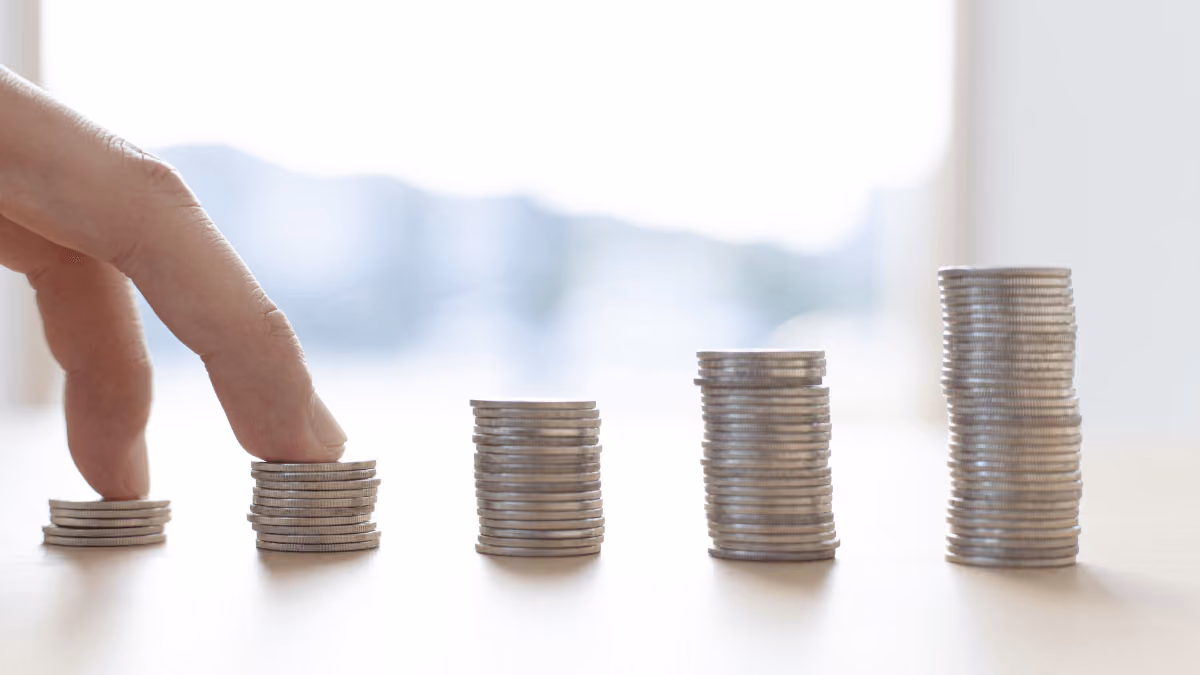Hand touching growing stacks of coins representing financial growth