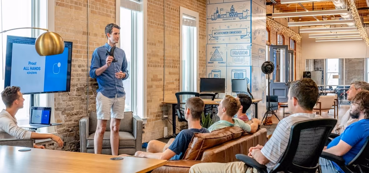 Presentation in modern office with men seated and presenter standing