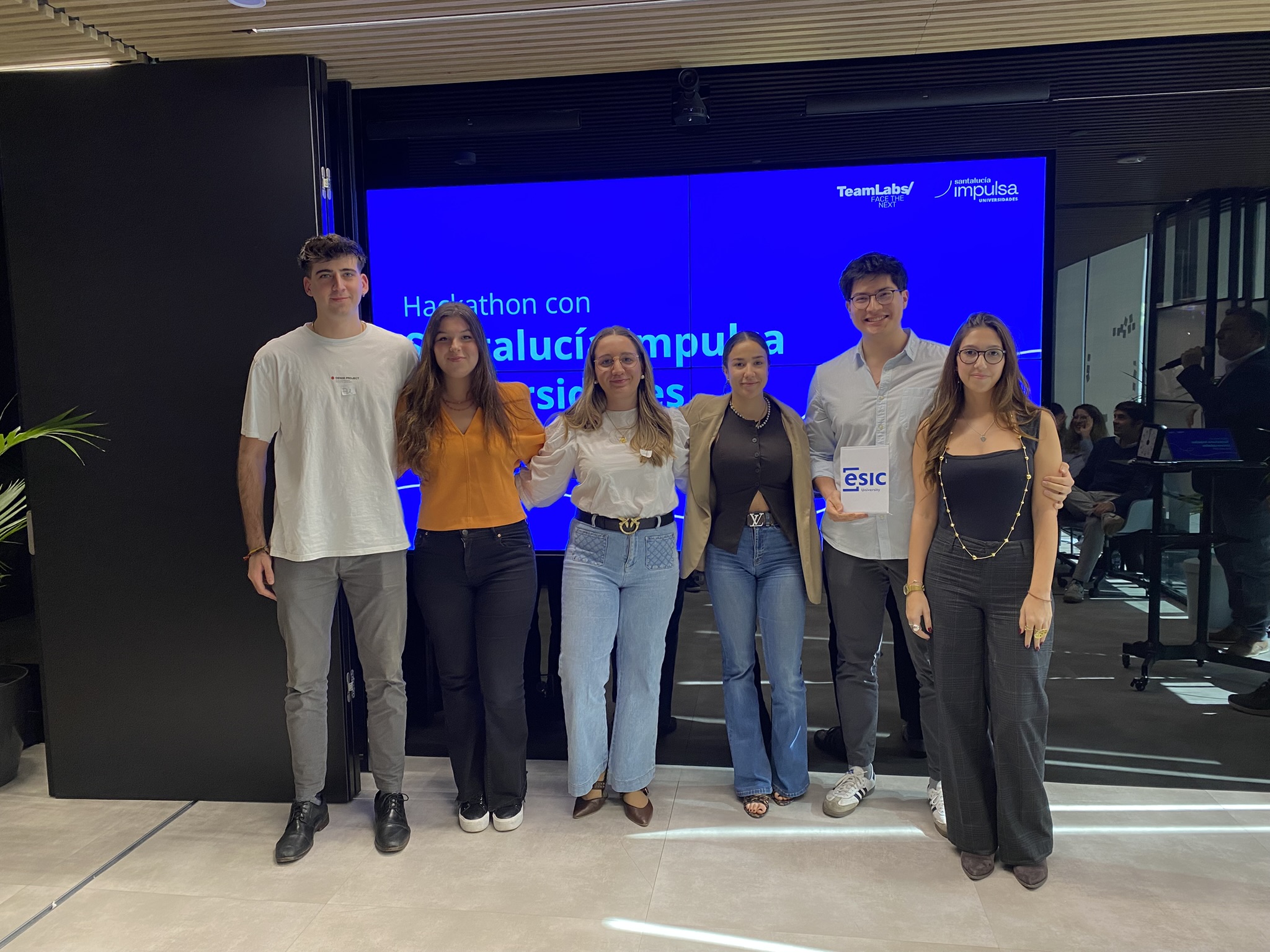 Grupo de estudiantes en hackathon de Andalucía Impulsa con pantalla azul