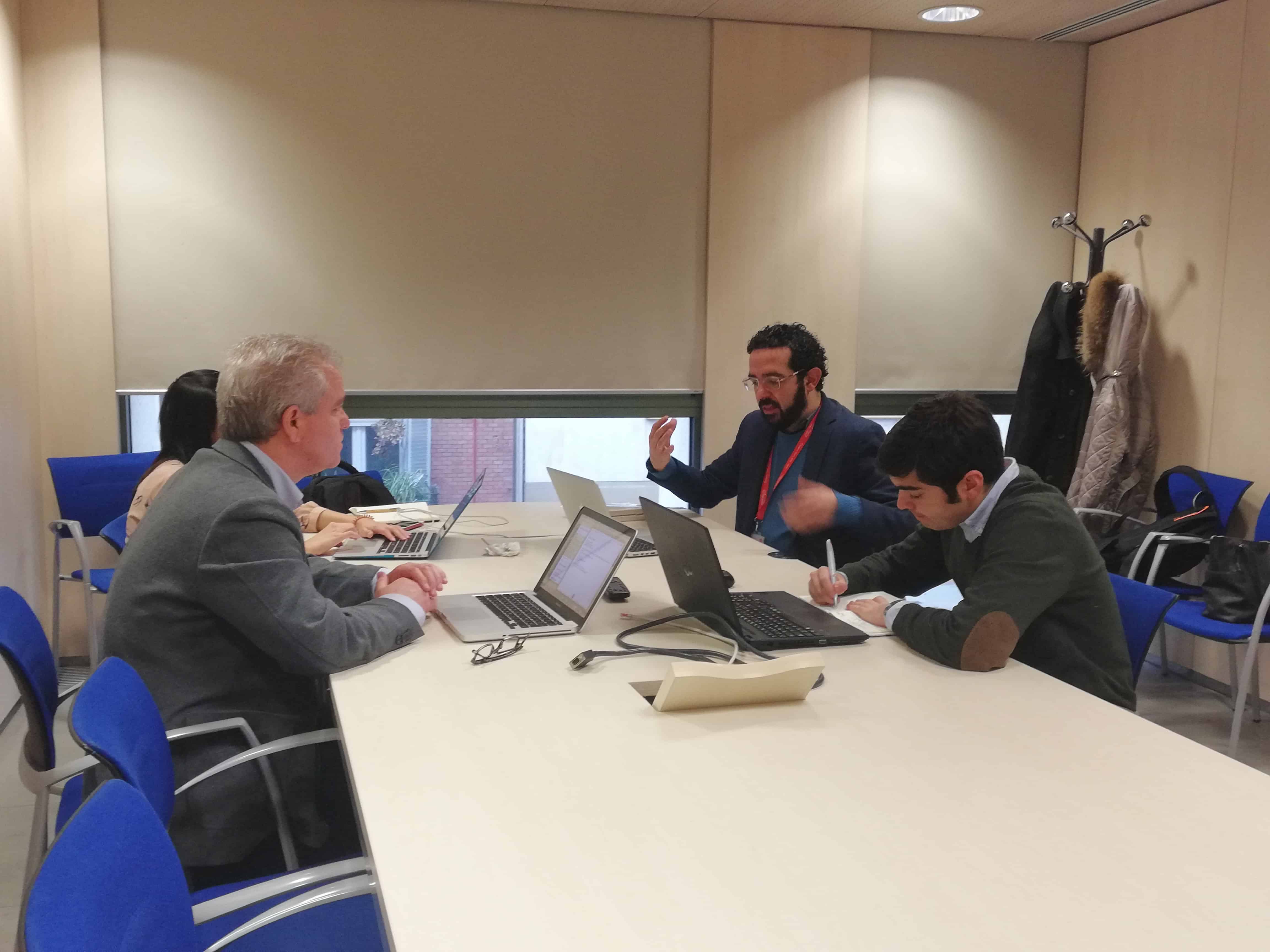 Reunión de trabajo con tres personas en una sala usando laptops