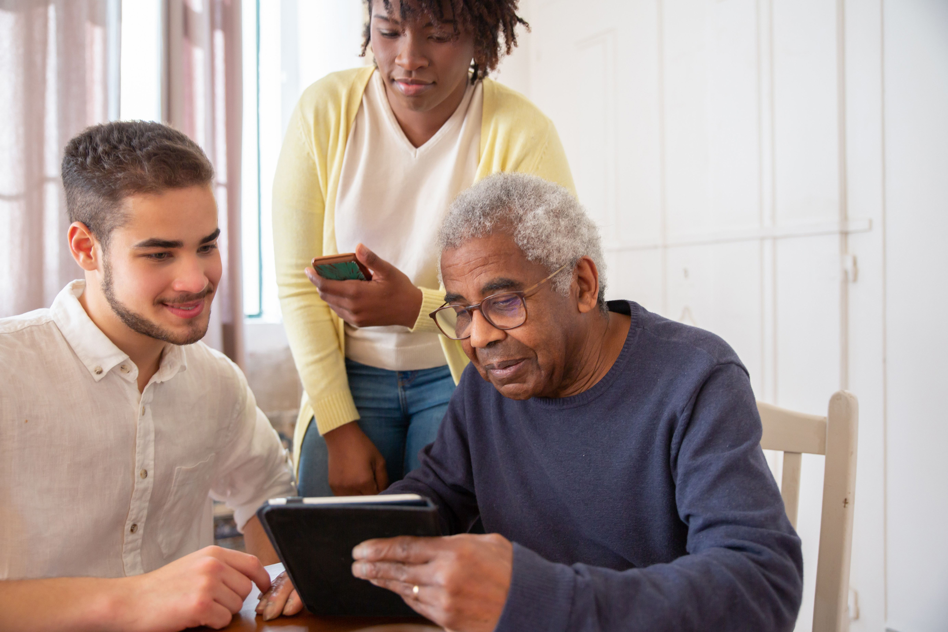 Aprendizaje digital intergeneracional con personas utilizando una tablet para adquirir competencias digitales y fomentar el aprendizaje continuo en el entorno laboral.
