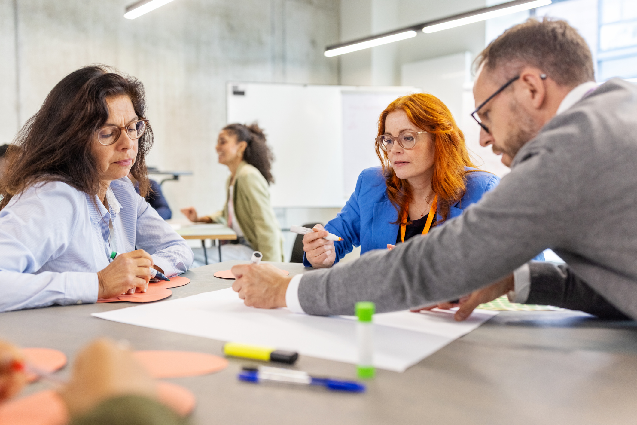 Workshop zur Visionsentwicklung bei Stadtwerken. 3 Personen sitzen am Tisch und arbeiten an der Vision.