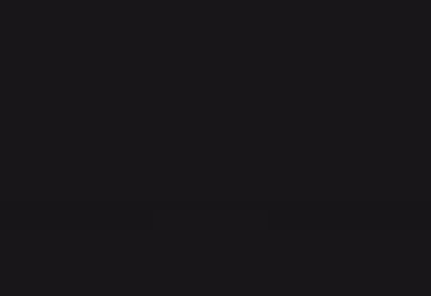 Two red sports cars parked side by side on a road in a mountainous area at sunset.