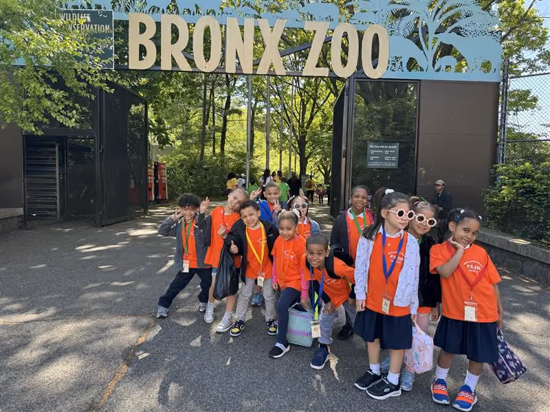 Students in orange school shirts posing at Bronx Zoo entrance