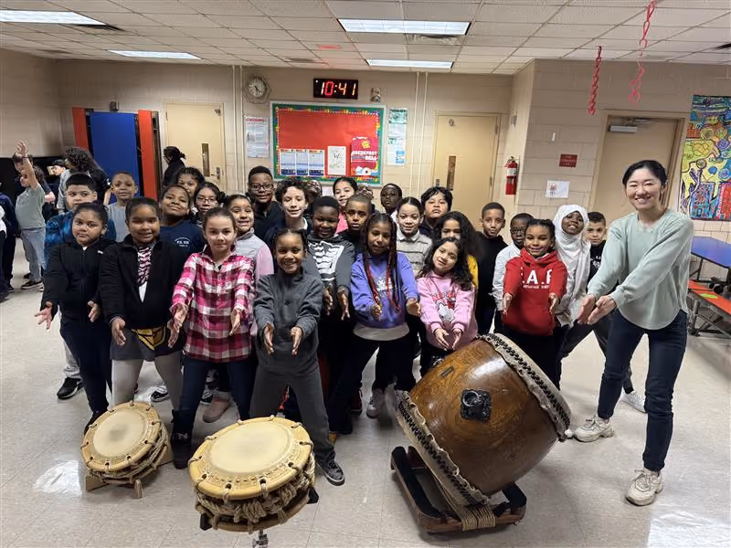 Students and teacher pose with traditional taiko drums during school music program