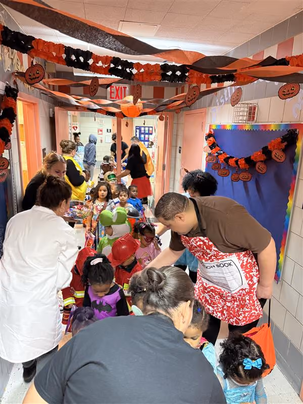 Students and staff trick or treating in a decorated school hallway