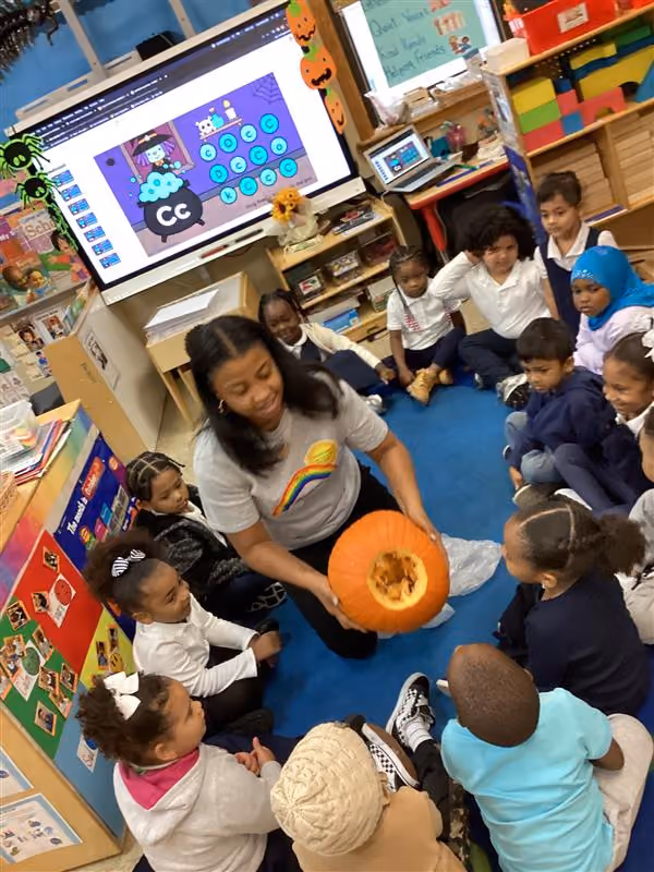 Teacher showing students a carved pumpkin during classroom lesson