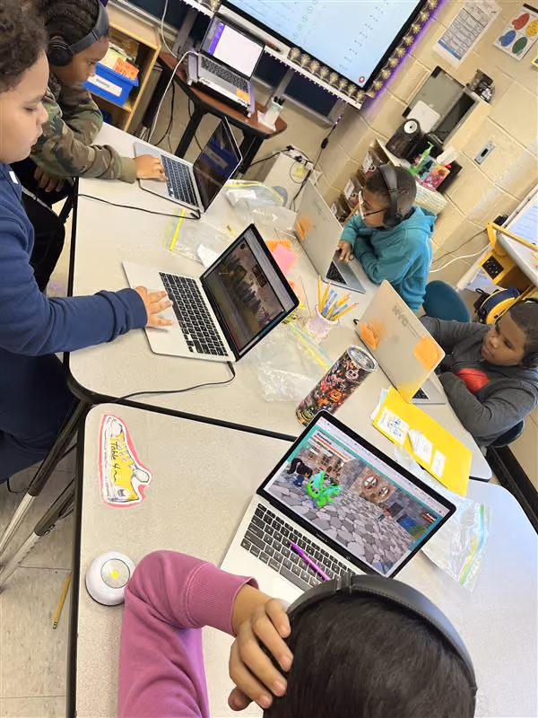 Students working on laptops with headphones in a classroom