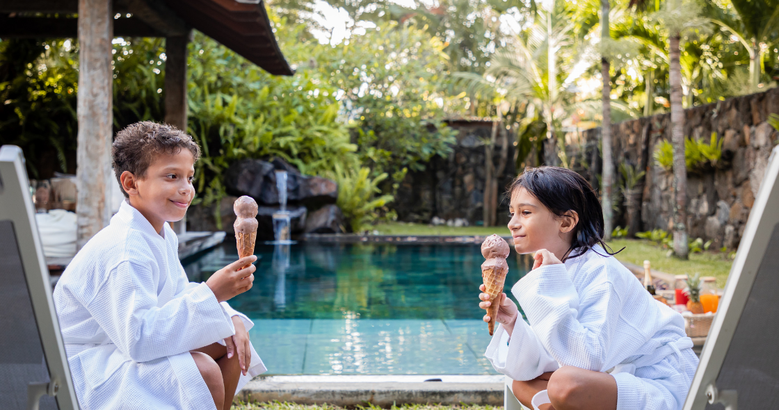 Two Kids Enjoying an Ice Cream in Front of A Private Pool