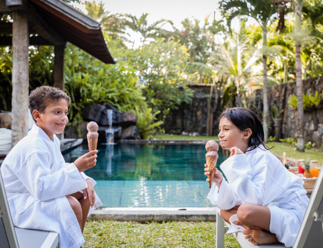 Two Kids Enjoying an Ice Cream in Front of A Private Pool 