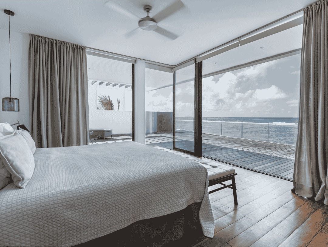 Minimalist bedroom interior with ceiling fan and stunning sea view.