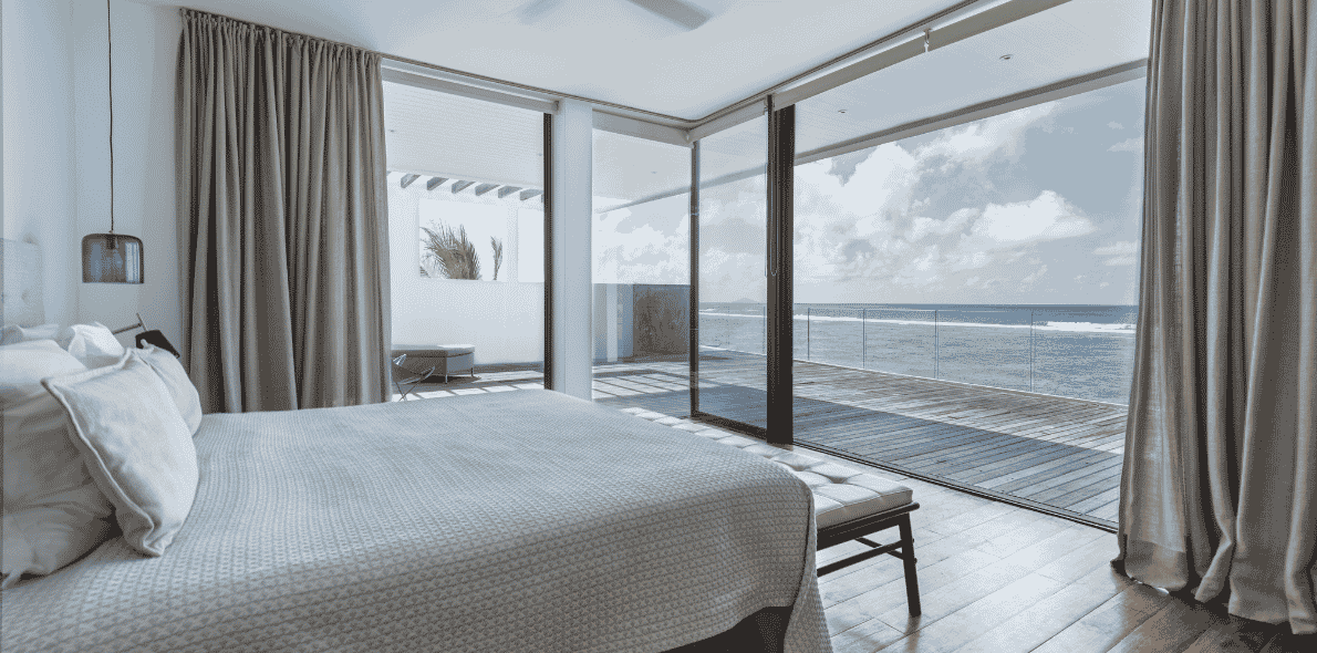 Minimalist bedroom interior with ceiling fan and stunning sea view.