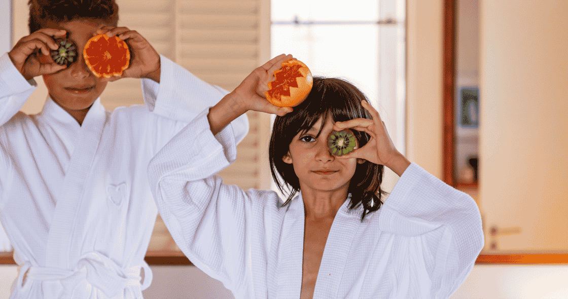 Un petit garçon et une petite fille s'amusent en tenant des tranches de fruits frais devant leur visage, comme s'il s'agissait de lunettes.