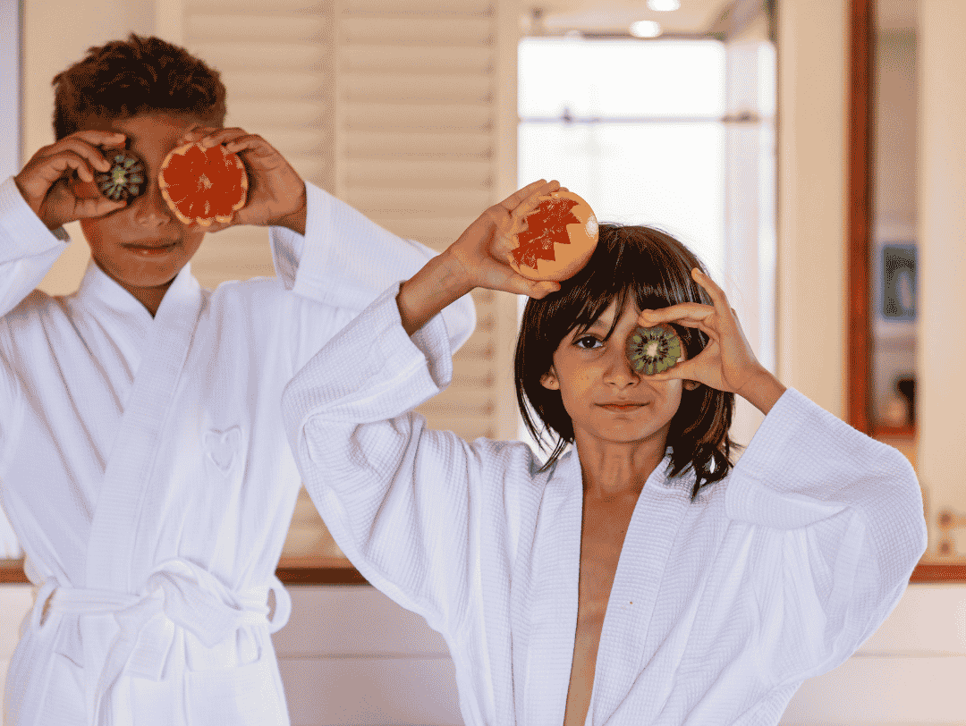 Un petit garçon et une petite fille s'amusent en tenant des tranches de fruits frais devant leur visage, comme s'il s'agissait de lunettes.