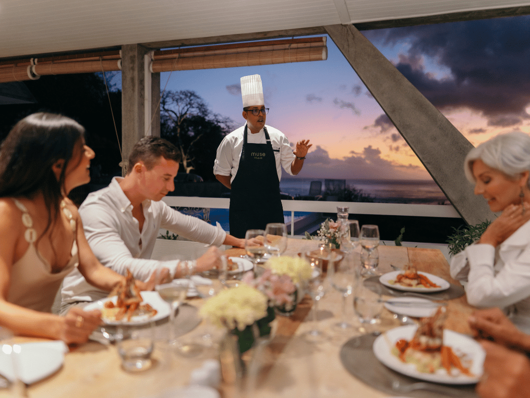 A professional private chef carefully plates a gourmet dish for guests during an exclusive in-villa dining experience.
