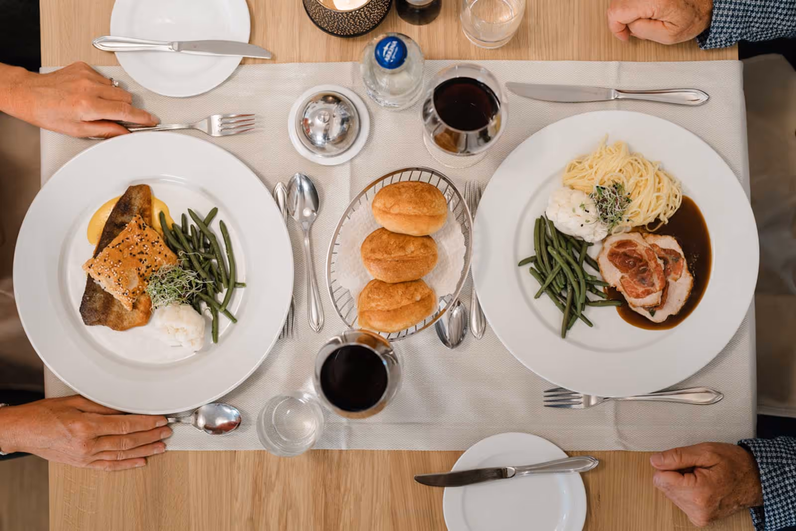 Table joliment dressée avec deux plats et du vin rouge