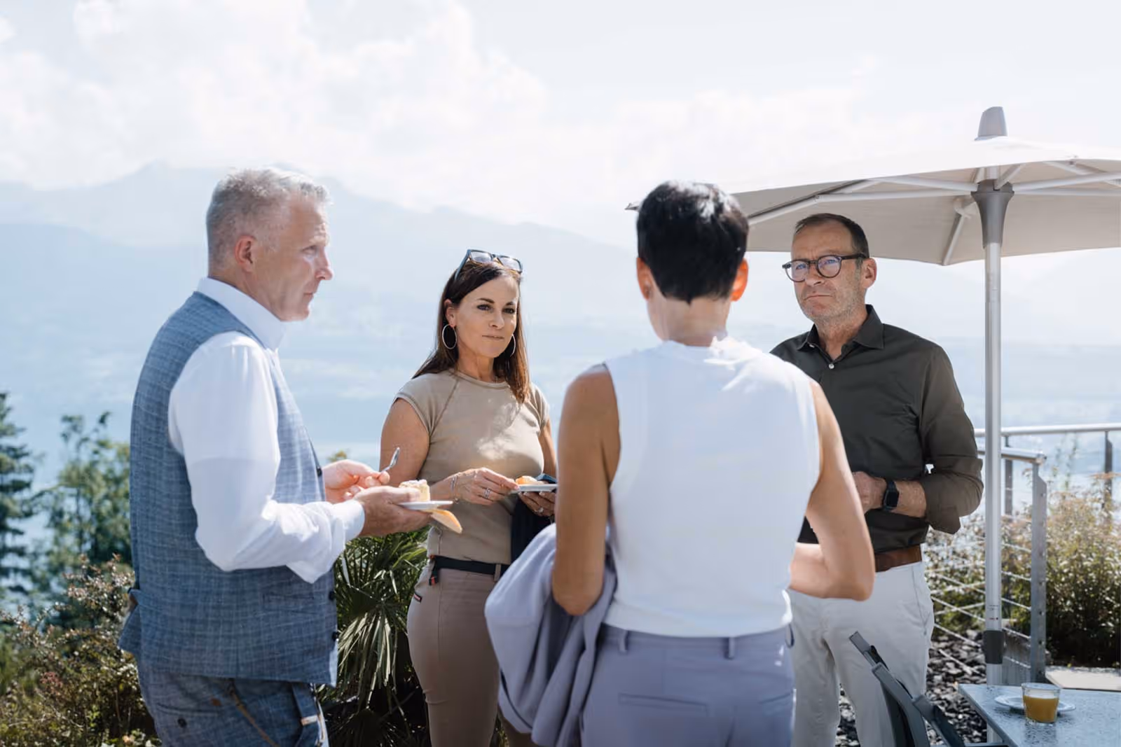 Quatre personnes prenant un café sur la terrasse surplombant le lac de Thoune