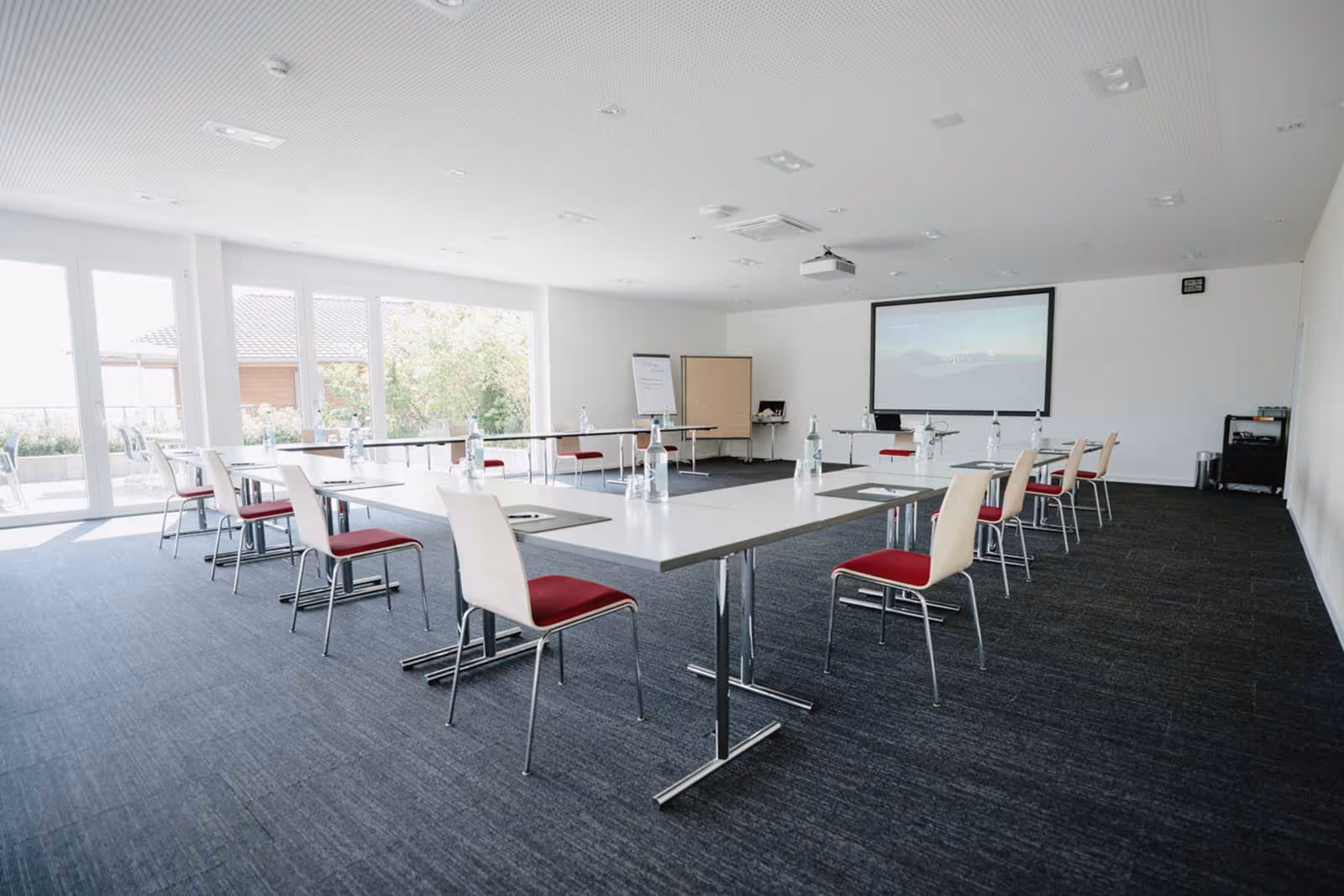 Salle de séminaire lumineuse avec chaises et écran de projection