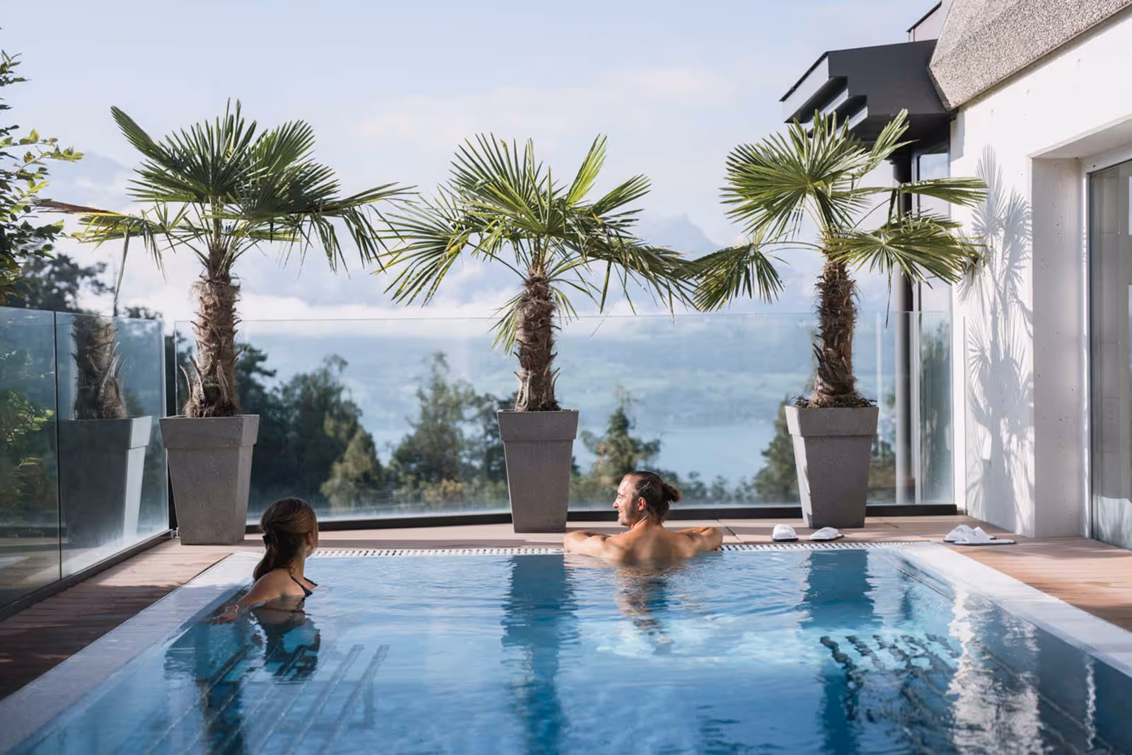 Deux personnes dans la piscine extérieure avec palmiers et vue