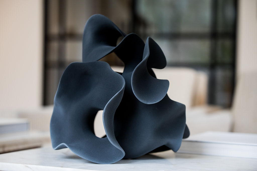 Handmade by renowned Belgian artist Liliane Demeester, this deep-black ceramic sculpture marries modern minimalism with the organic allure of Georgia O’Keeffe’s flower forms. The piece swells and tapers in a rhythmic flow, its satin-matte surface catching light along every voluptuous contour. Whether displayed on a console, mantel, or gallery pedestal, the sculpture feels almost alive—breathing, unfurling, and inviting touch. Fired at high temperature for lasting strength, each limited-edition work is signed and accompanied by a certificate of authenticity, making it a coveted statement for collectors of contemporary art and luxury interior décor.