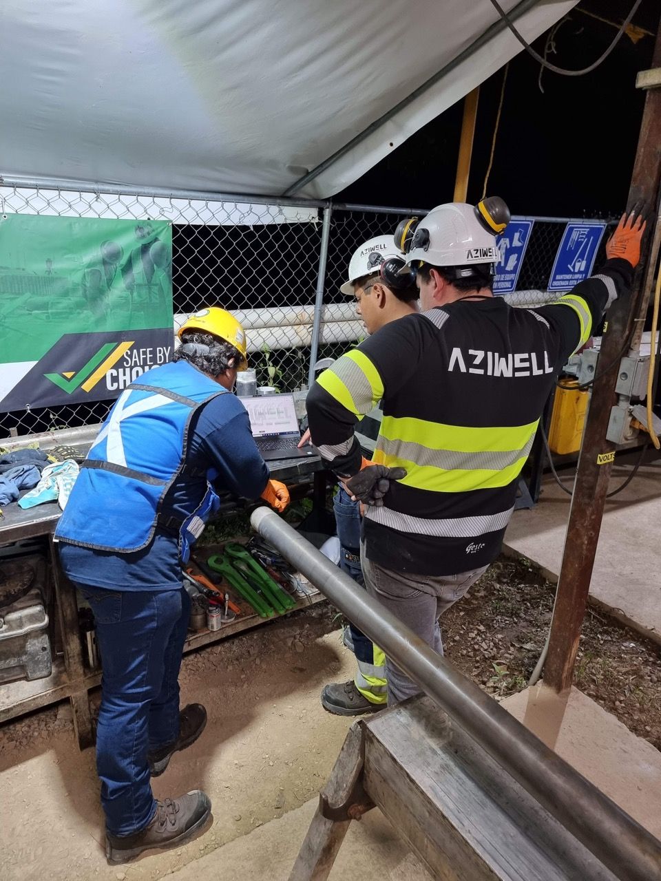 Aziwell operators discussing charts on a computer while hunched over a table