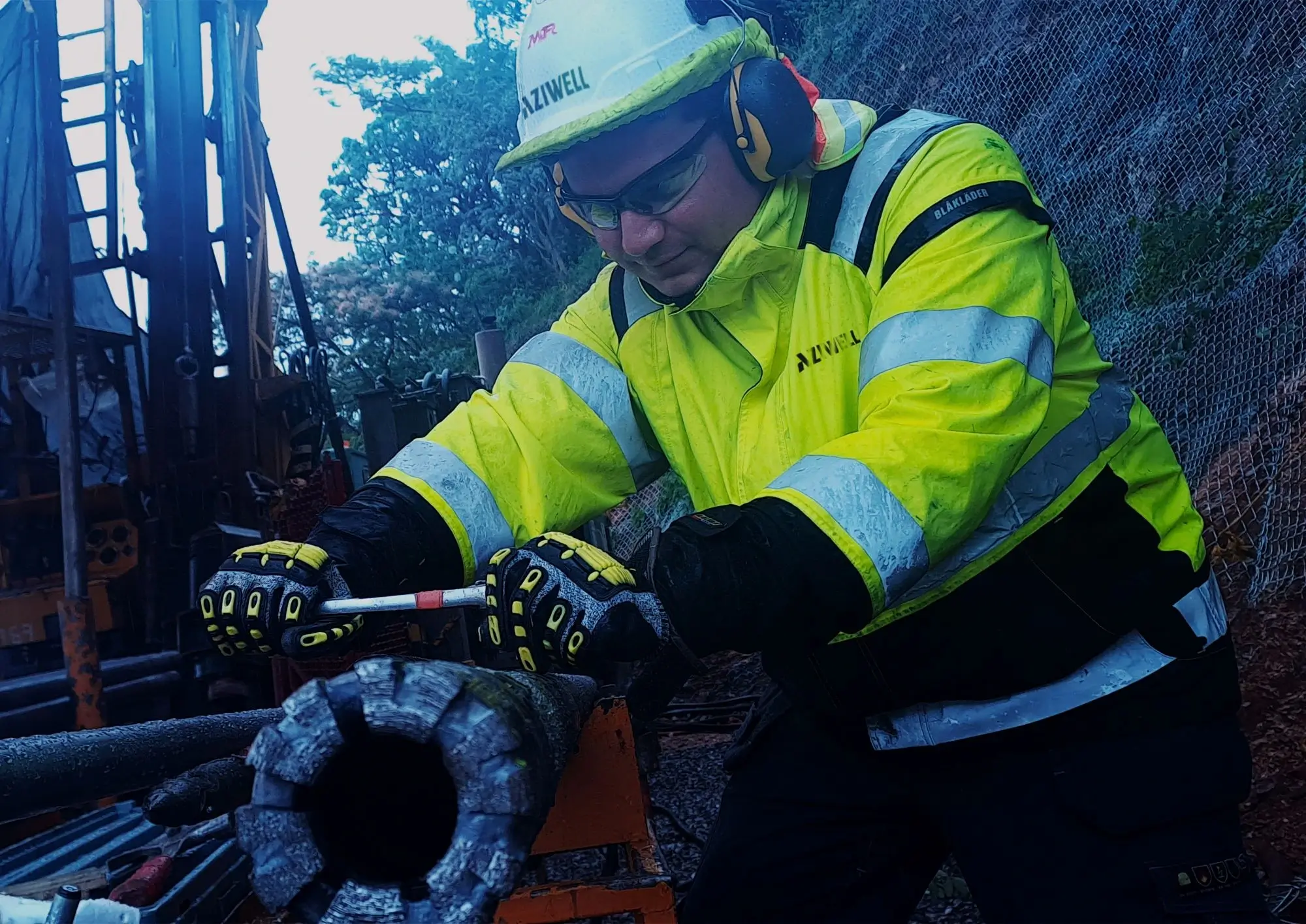 Un operario de Aziwell con equipo de seguridad inspeccionando una corona de perforación diamantada en un sitio de exploración minera, representando el proceso de extracción de muestras de cobre.