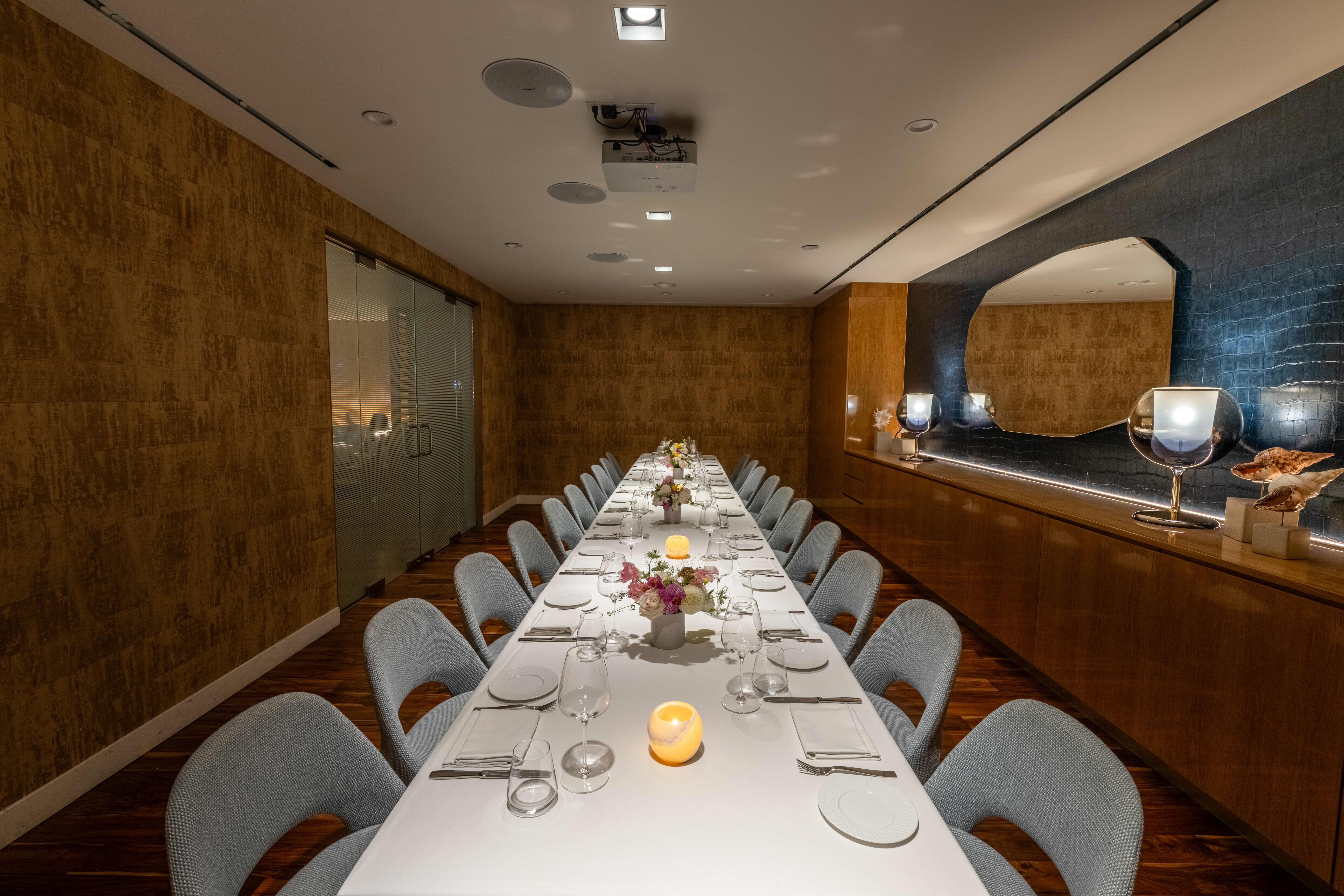 marea beverly hill's amalfi private dining room - light wood and beige walls with red artwork. a long rectangular table with a white tablecloth