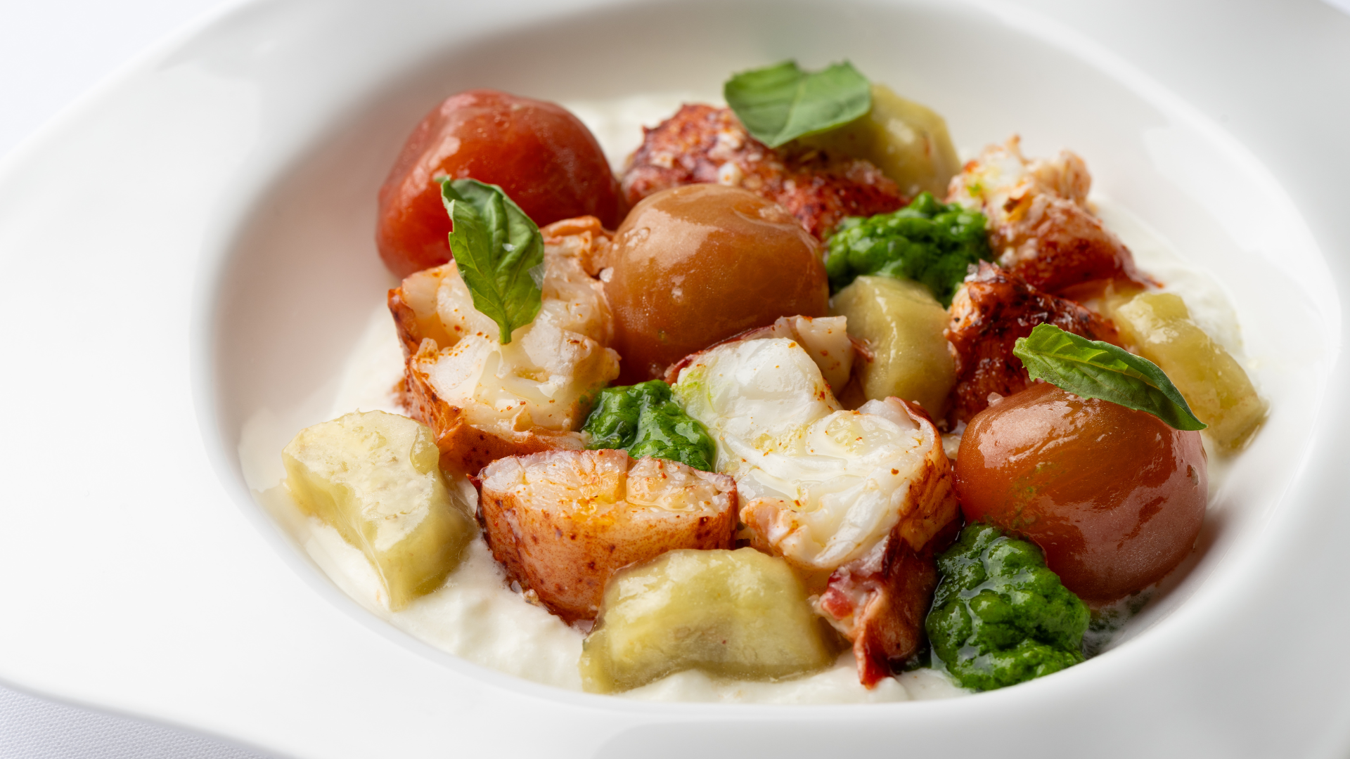 A refined coastal Italian table setting featuring a sparkling rosé cocktail being topped with Champagne, surrounded by elegantly plated dishes including grilled langoustines, crudi, fresh avocado, olive oil, and artisanal bread on a white tablecloth—capturing the elevated dining experience of Marea.