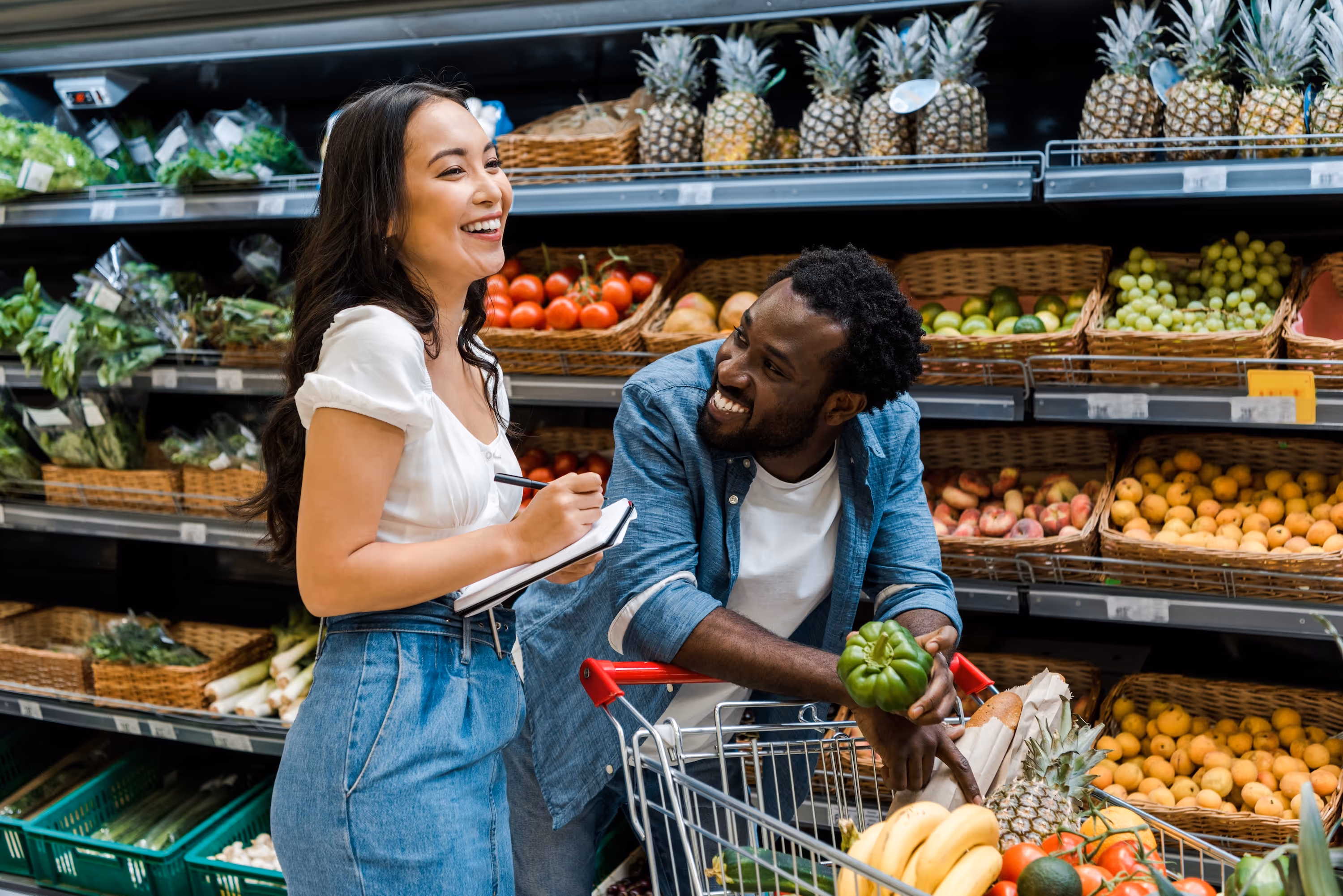 A happy couple smiling while grocery shopping for fresh produce, representing the convenience of local amenities near The Abbey in Greenville, SC.