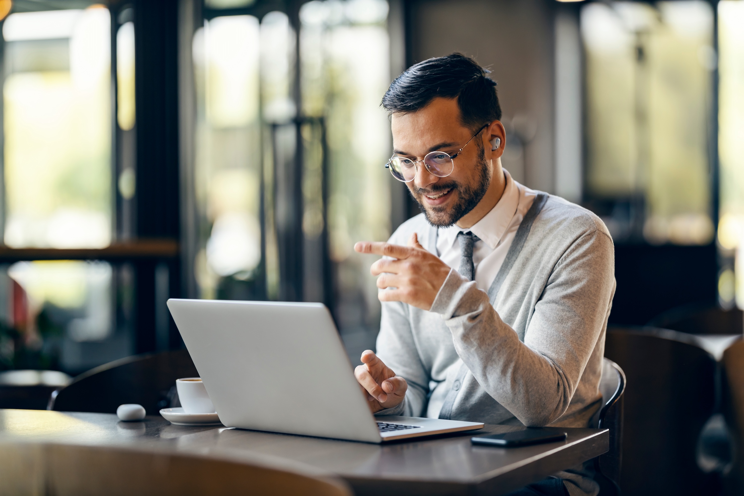 Young professional working remotely with a laptop and coffee, showcasing the hybrid lifestyle available to residents near The Abbey