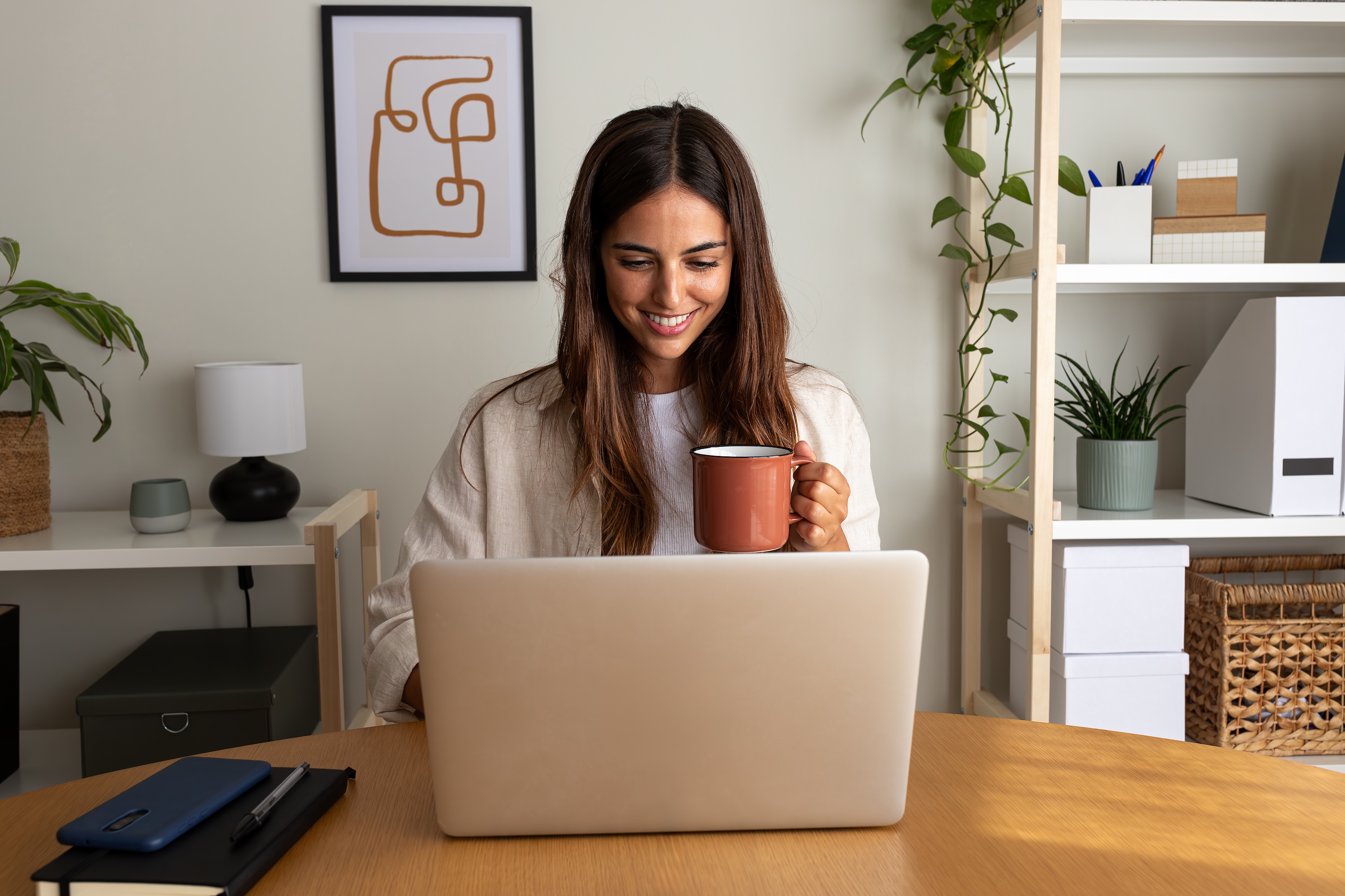 Resident drinking coffee while using a laptop at a home office desk at The Abbey in Greenville, SC