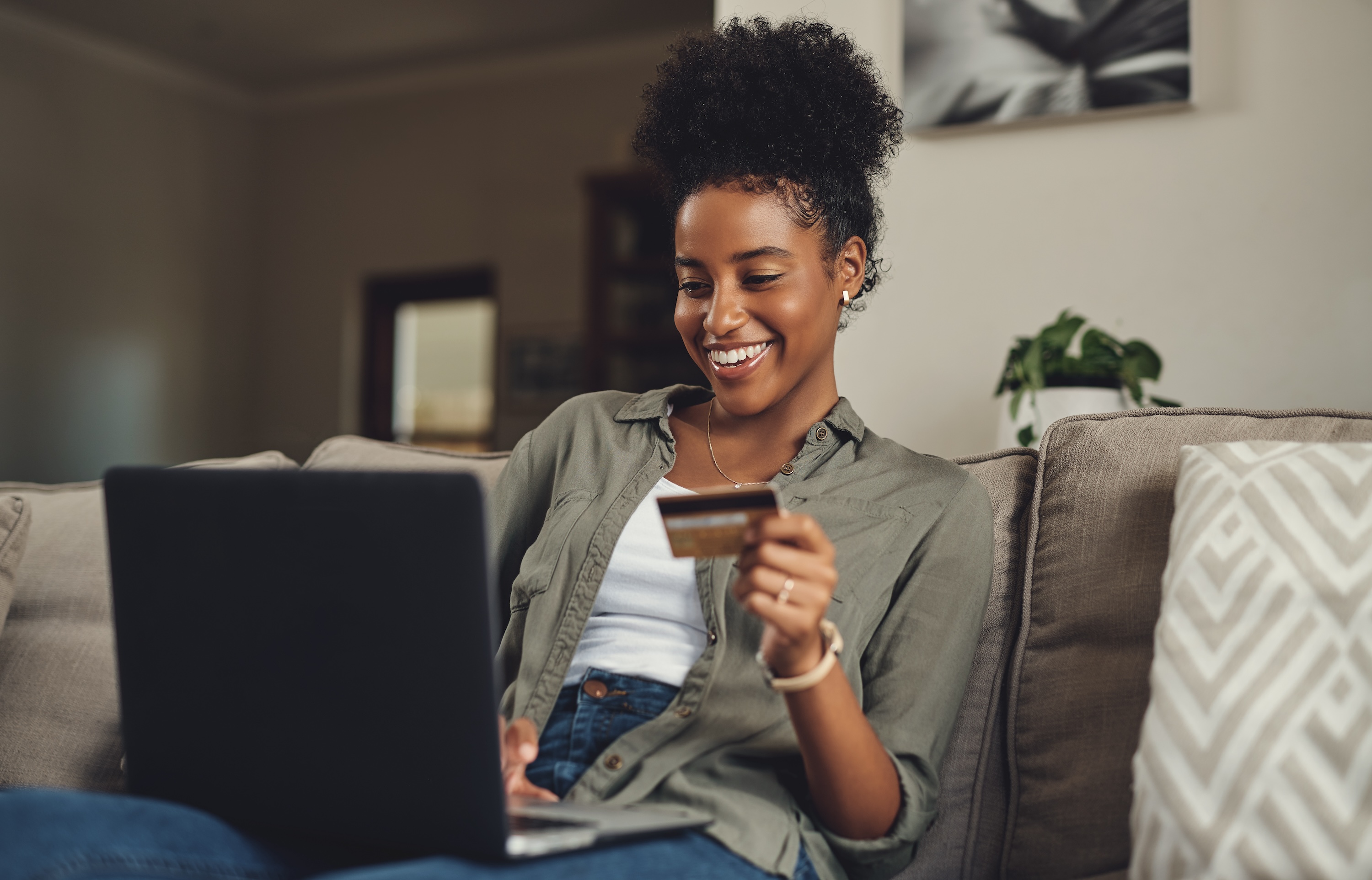 Resident paying online with a card and laptop on a living room sofa at The Abbey in Greenville, SC