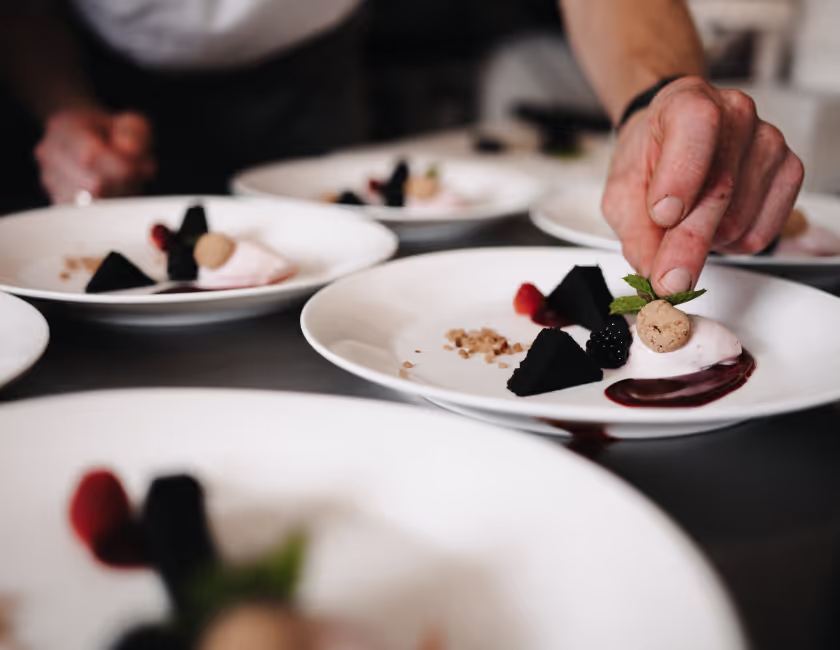 Hand versiert gastronomisch dessert op witte borden in professionele keuken.