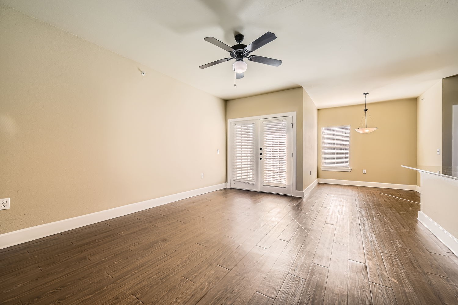 Empty living room with doors to balcony and ceiling fan