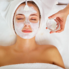 Woman receiving a facial treatment with a handheld device from a technician wearing black gloves.