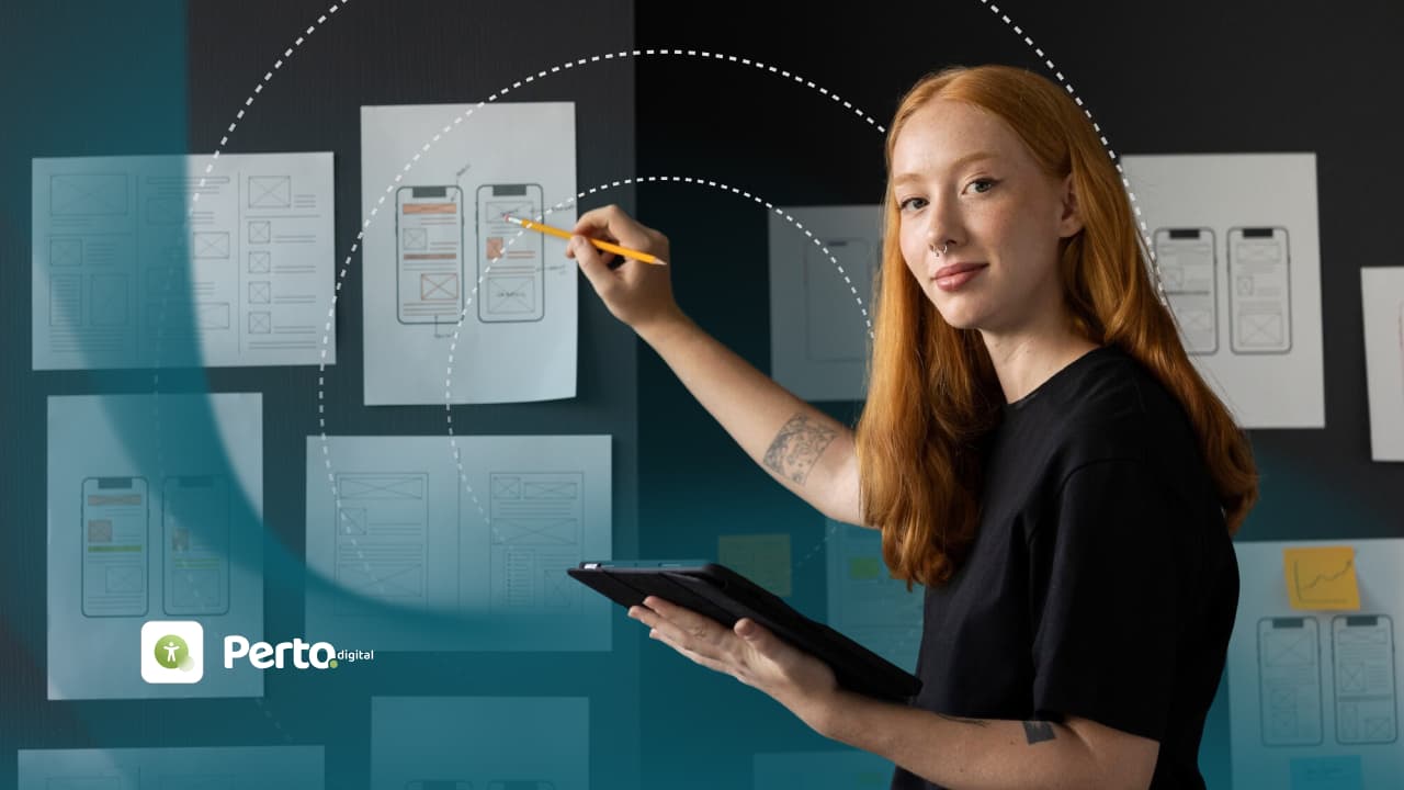 Designer revisa esboços de wireframes de telas mobile fixados em um mural, enquanto segura um tablet.