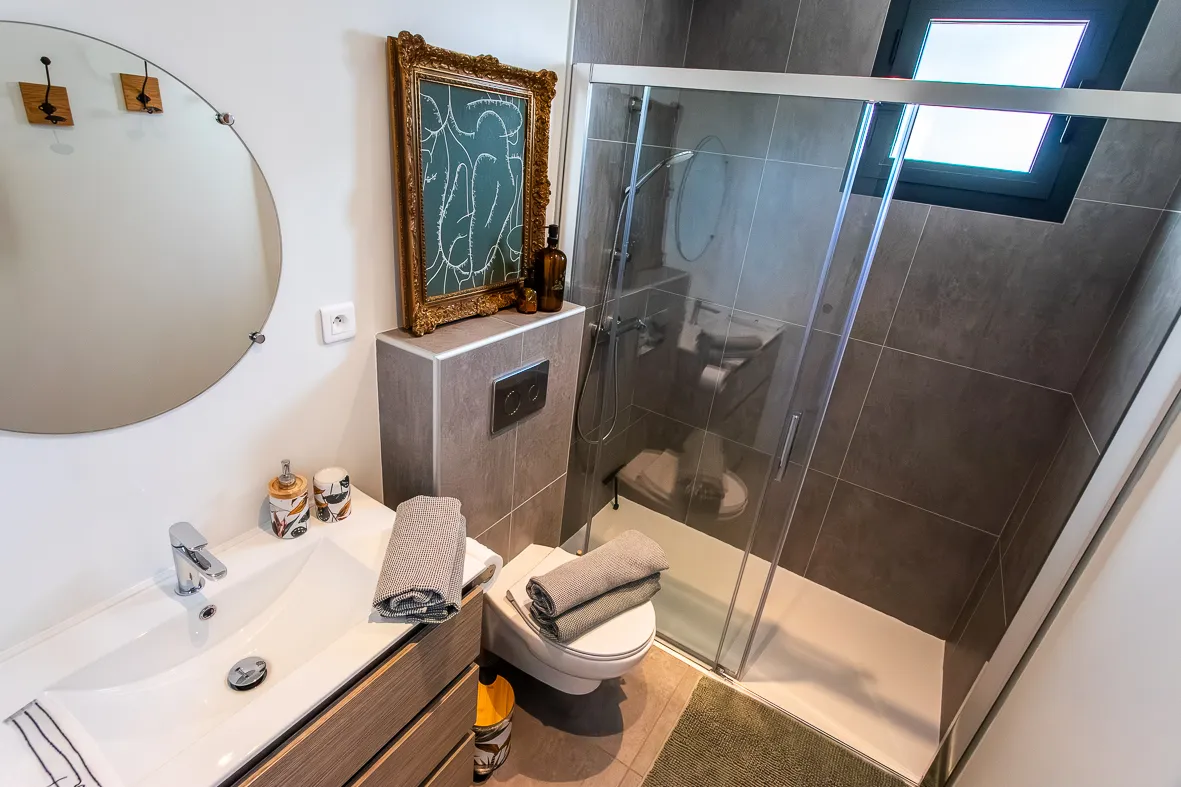Salle de bain moderne et spacieuse avec une grande douche à l'italienne, parfaite pour se détendre après une journée de randonnée dans l'Aude.
