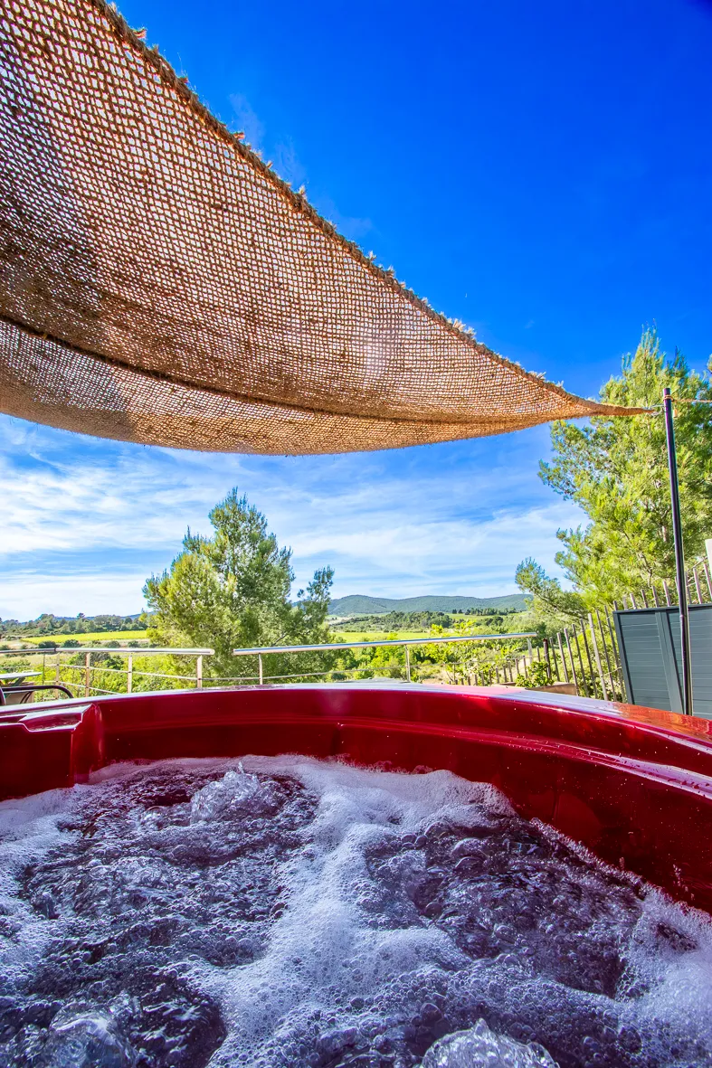 Jacuzzi extérieur avec vue panoramique sur la garrigue et les vignes.